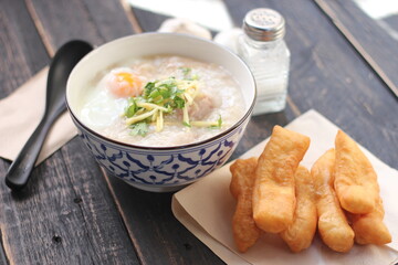 Joke or Congee in a Thai style cup Served on a black wooden table. It's an Asian breakfast.