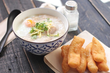 Joke or Congee in a Thai style cup Served on a black wooden table. It's an Asian breakfast.