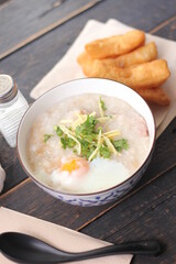 Joke or Congee in a Thai style cup Served on a black wooden table. It's an Asian breakfast.