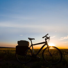 Fototapeta na wymiar bicycle silhouette in prairie at the dramatic sunset, outdoor travel sport scene