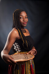 Young beautiful African fashion model in traditional dress with an ethnic bowl.