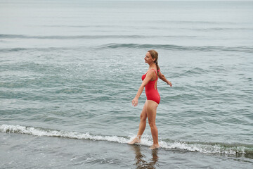 girl in a red swimsuit walking on the beach