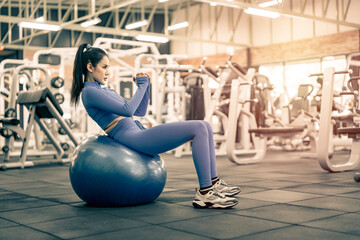 Asian woman doing exercise on fitness ball at gym.