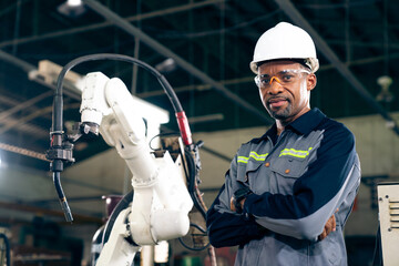African American factory worker working with adept robotic arm in a workshop . Industry robot...