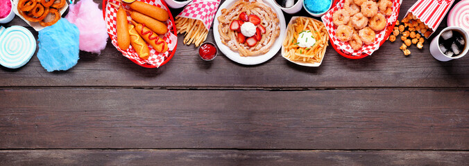 Carnival theme food top border over a dark wood banner background. Overhead view with copy space....