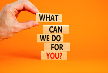 Support symbol. Concept words What can we do for you on wooden blocks on a beautiful orange table orange background. Businessman hand. Business motivational and support concept.