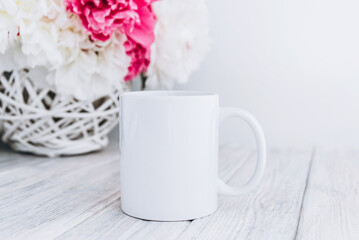 Obraz na płótnie Canvas Mock up of white blank coffee mug perfect for your own design or quote with peony flowers on background.