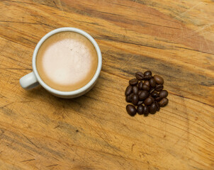 Coffee cup and coffee beans on a wooden table, expresso cenital view