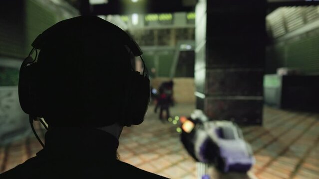 caucasian man in black hat and headste playing in an old fist person shooter video game in front of big screen