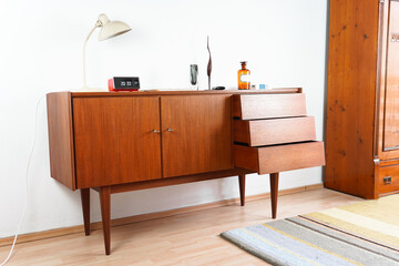 a vintage 60s mid century sideboard cupboard made out of teak wood in denmark standing in the living room danish design high quality decorated furnished 20s lamp