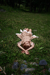 Pretty young girl lies on the green meadow under sun rays.