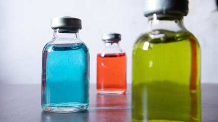 drug vial contain blue, red, and green solution. The blue solution is focused at the left.