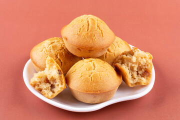 Homemade rice muffins with raisins on a beautiful white saucer on a brown (pink) background. Rice flour cupcakes. The concept of proper nutrition, a gluten-free diet.
