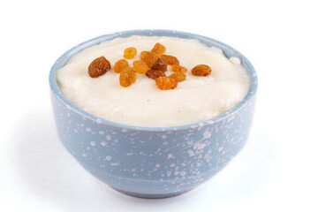 Semolina porridge with delicious brown raisins in a blue plate (bowl) on a white isolated background, close-up, side view. Cereals contain gluten. Design, template.