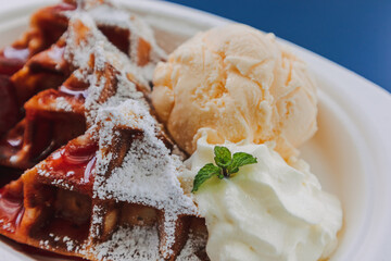 Dessert set of ice-cream waffle with cherries served on blue table.