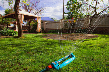 Garden sprinkler with water hose in the backyard