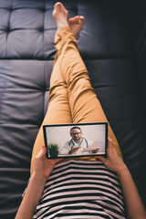 Woman lying on a sofa and talking with a doctor online using digital tablet. Telemedicine concept.