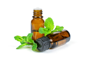 Essential oil of fragrant mint (peppermint) in two dark glass bottles with a dispenser and lid on a...