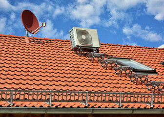 Klimaanlage, Luftw&auml;rmepumpe, Dachtreppe und Satelliten-Anlage auf dem Ziegeldach eines  Wohnhauses