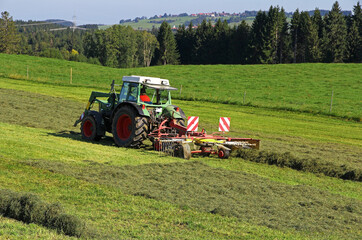 Obraz premium Heuernte mit einem Traktor auf einem Feld im Oberallgäu
