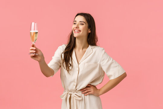 Girl Giving A Speech During Bachelorette Party. Cheerful And Happy Smiling Carefree Young Woman In Dress, Raising Glass Champagne Laughing And Grinning, Congratulating With Birthday, Pink Background