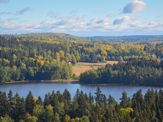 Panorama from top of Aulanko lookout tower near the Finnish town Hamenlinna: forests, lake, colorful trees, clouds.