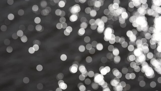 Black and white round bokeh lights on water surface. Summer time, sunny weather.