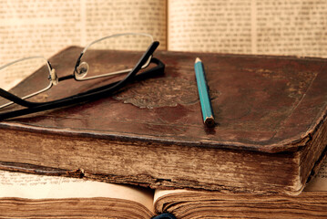 Old worn shabby jewish books in leather binding and open blurred Torah in the background. Closeup....