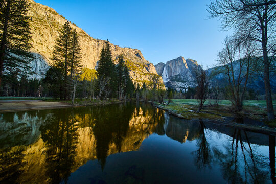 Golden hour on river at Yosemite with Upper Falls in distance
