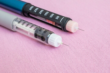 Insulin pen injector. Insulin pen fill with needle on pink background. Diabetes Day.