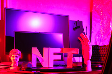 NFT Non-Fungible Token and computer equipment in pink neon light. NFT inscription with antique statue and artificial arm. Concept of metaverse and blockchain technology