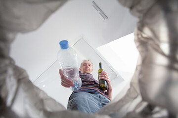 Male hand trowing a plastic bottle into a garbage bin