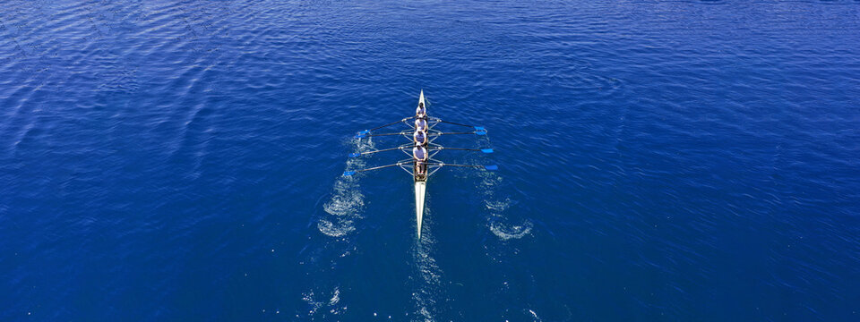 Aerial drone top ultra wide panoramic view of sport canoe rowing synchronous team of athletes competing in deep blue sea