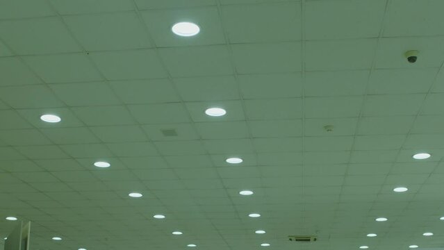 Many Circle Led Lamps Built Into The Ceiling Glowing In The Dark . To Include And Switch Off . White Rounded Lights Turns On Alternately On Ceiling Of Dark, Industrial Room. Lighting Equipment Concept