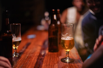 African men at beer bar, glass on wooden desk in evening, detail to drink