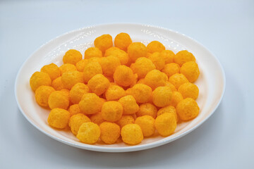 Selective focused cheese puff balls.  Pile of cheese balls isolated on white background. Plate full of cheese puff balls isolated