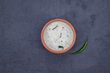 Fresh made Indian food, chutney, Coconut chutney in a bowl with raw coconut. Served with dosa, idli, vadai, Pongal. Selective focused home made coconut chutney in isolated white background.