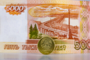 The coin of Belarus on the background of the banknote of Russia. A concept for currency exchange, the Belarusian ruble for the Russian ruble. Selective focus, close-up. 
