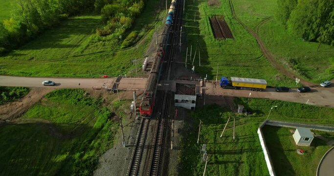 Railway crossing aerial view. Freight train. Sunlight before sunset.