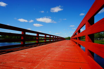 A red wooden bridge used to cross a river in a park
