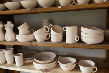 Fototapeta na wymiar Ceramic pots, plates and cups in clay on wooden shelves. Eco friendly pottery set handmade