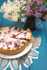 Homemade summer berry pie with a bouquet of lilacs.
