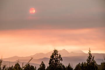Wildfire smoke and sun over silhouetted mountains in Oregon high desert