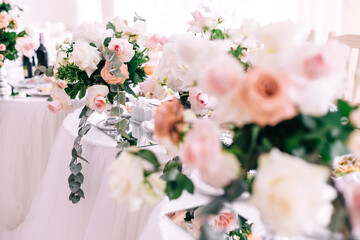 Wedding decoration table in the hall, floral arrangement. In the style vintage. Decorated dining table with flowers for guests and newlyweds, in peach-pink, pastel color.