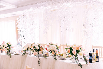 The elegant area of the Newlyweds table is decorated with flowers and illuminated with light of different colors. Beautiful flower decoration of the wedding venue and ceremony, details