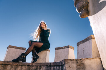 Young woman sits on the wall of Palace of Pena in Portugal - LISBON - SINTRA. PORTUGAL
