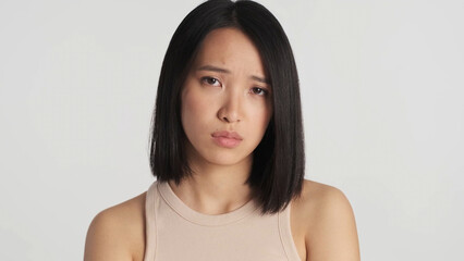 Upset Asian woman unhappy because of bad news isolated.  Female looking sad over white background....