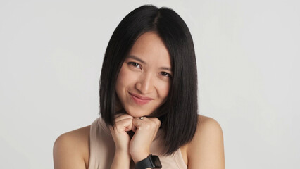 Asian girl looking cute at camera isolated on white background. Pretty female smiling as hearing...