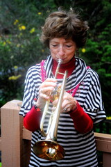 Female senior trumpet player blowing her horn outside.
