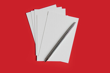 white postcard template with pen on red background.